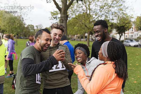 Freundschaftsläufer mit Smartphone beim Charity-Lauf im Park