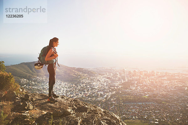Weibliche Klettererin auf dem Hügel mit Blick auf die sonnige Stadt