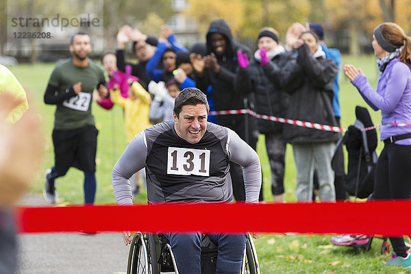 Entschlossener Mann im Rollstuhl  der sich dem Ziel des Benefizrennens im Park nähert.