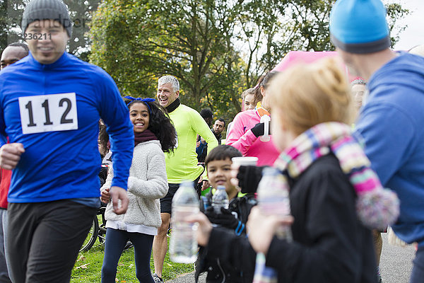Zuschauer bieten Wasser für Läufer beim Charity-Lauf im Park an