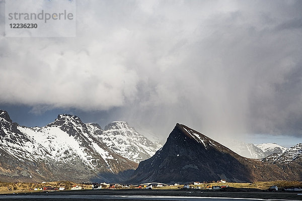 Dramatische Wolken über abgelegenen  verschneiten Bergen  Fredvang  Lofoten  Norwegen