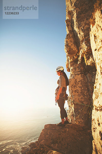 Weibliche Klettererin mit Blick auf das sonnige Meer