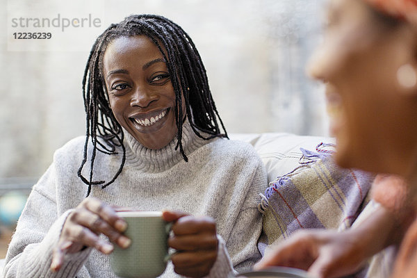 Enthusiastische  lächelnde Frau  die einem Freund zuhört und Kaffee trinkt.