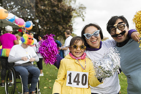 Porträt einer verspielten Familie mit alberner Brille beim Charity-Lauf im Park