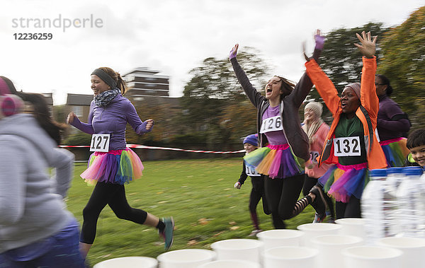 Enthusiastische Läuferinnen im Tutus jubeln  Laufen beim Charity-Rennen im Park