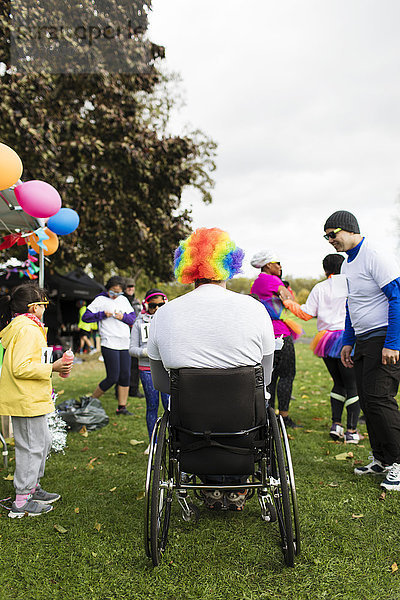 Mann im Rollstuhl mit Clown-Perücke beim Charity-Rennen im Park