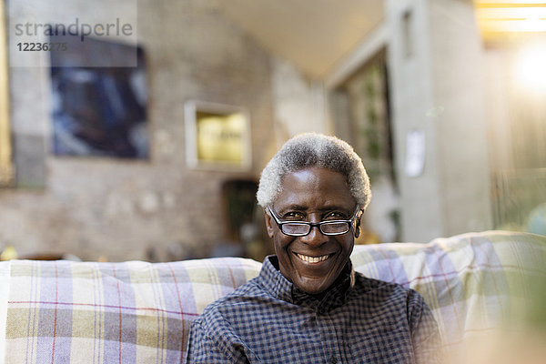 Porträt lächelnder  selbstbewusster Senior auf dem Sofa