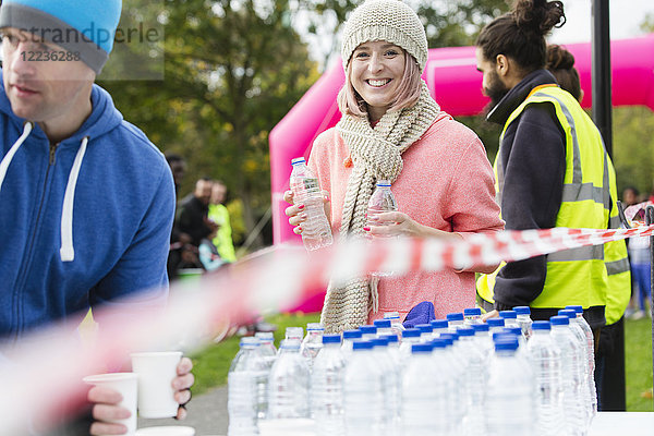 Porträt einer lächelnden Freiwilligen  die beim Spendenlauf Wasser austeilt