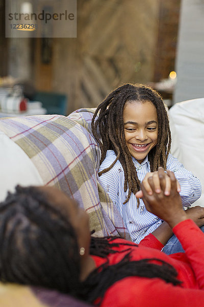 Liebevolle Mutter und Tochter halten Hände auf dem Sofa