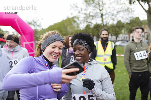 Läuferinnen mit Smartphone beim Charity-Lauf im Park