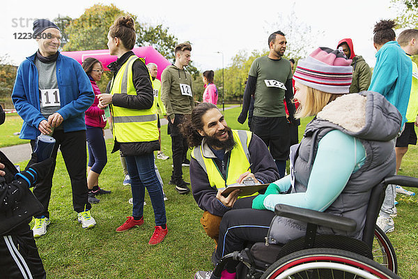 Frau im Rollstuhl beim Einchecken mit Freiwilliger beim Charity-Rennen im Park
