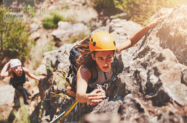 Fokussierte  entschlossene Klettererin am Fels hängend