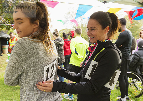 Mutter pinnt Marathon-Lätzchen auf Tochter beim Benefizlauf im Park