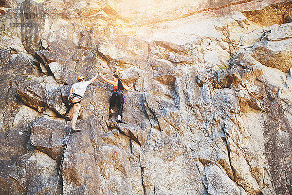 Felskletterer hochfliegend an der Felswand