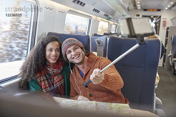Fröhliches junges Paar nimmt Selfie mit Selfie-Stick im Personenzug