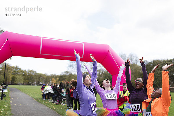 Begeisterte Läuferinnen im Tutus jubeln  feiern beim Charity-Lauf im Ziel