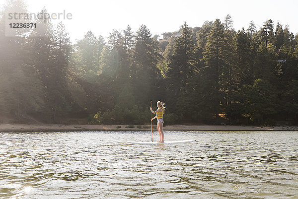 Frau beim Paddeln auf dem sonnigen  ruhigen See