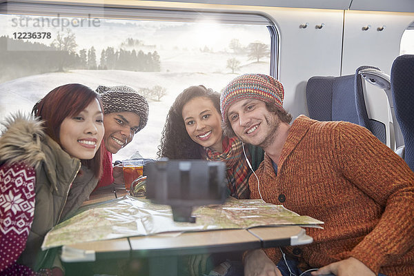 Glückliche junge Freunde mit Karte  die Selfie mit Selfie-Stick im Personenzug nehmen