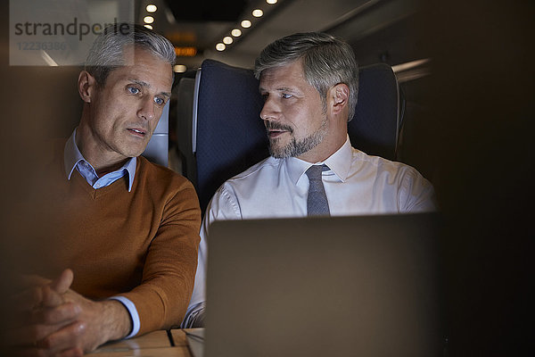 Geschäftsleute reden  nachts am Laptop im Personenzug arbeiten