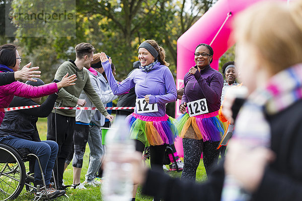 Weibliche Läuferinnen mit hochkarätigen Zuschauern beim Charity-Lauf im Ziel