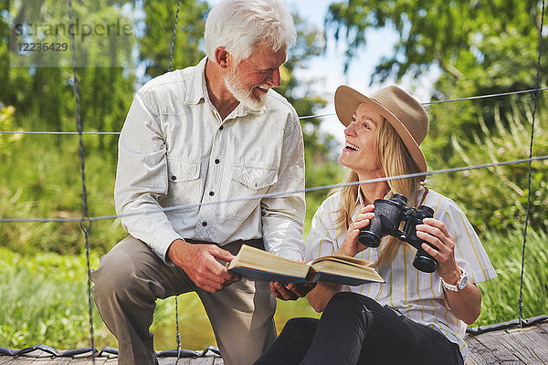 Lächelndes aktives Ehepaar Vogelbeobachtung mit Fernglas und Buch