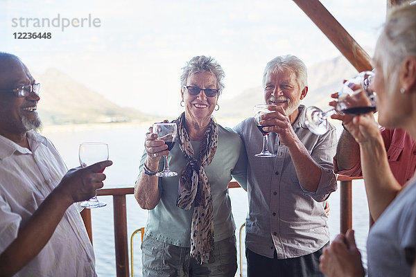 Glückliche aktive Seniorenfreunde beim Weintrinken auf dem Balkon