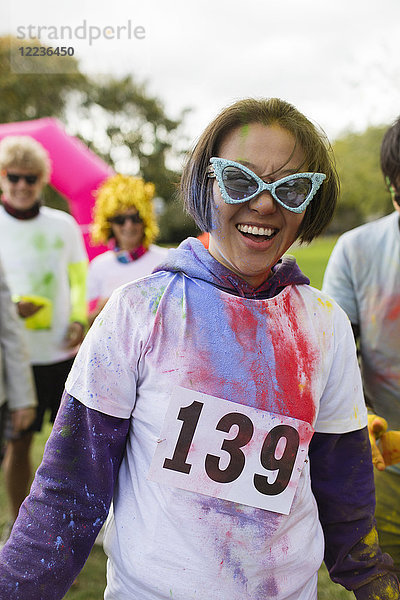 Portrait verspielte Läuferin mit Sonnenbrille und holi powder beim Charity-Lauf im Park