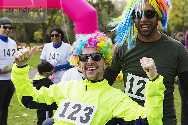 Portrait begeisterte männliche Läufer mit Perücken beim Benefizlauf