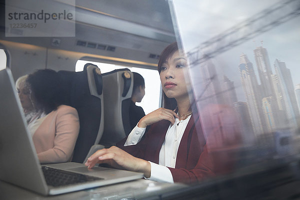 Fokussierte Geschäftsfrau bei der Arbeit am Laptop im Personenzug