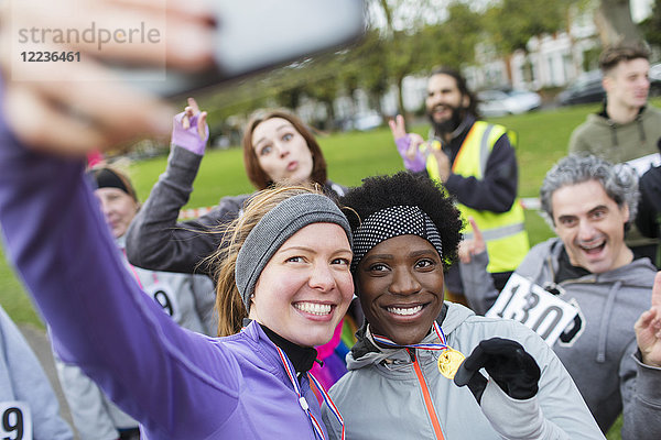 Lächelnde Läuferinnen mit Medaille beim Charity-Lauf im Park