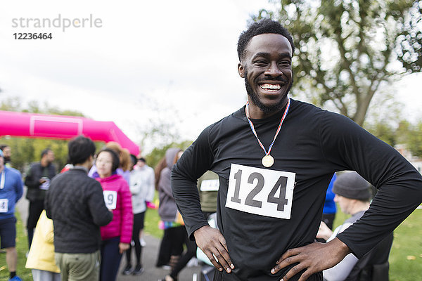 Portrait glücklicher  selbstbewusster Läufer mit Medaille beim Charity-Lauf im Park
