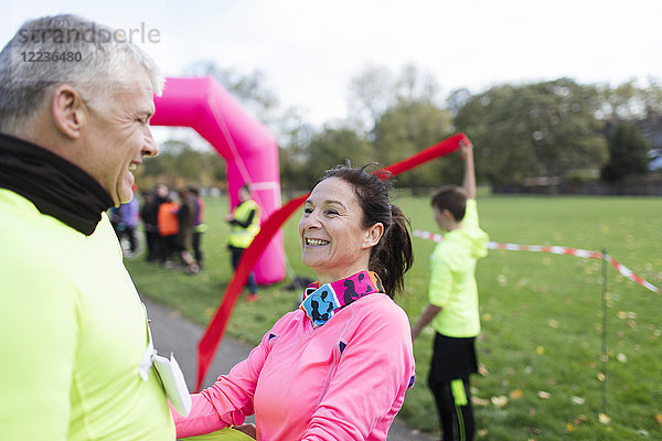 Glückliche Läufer überqueren die Ziellinie beim Charity-Lauf im Park