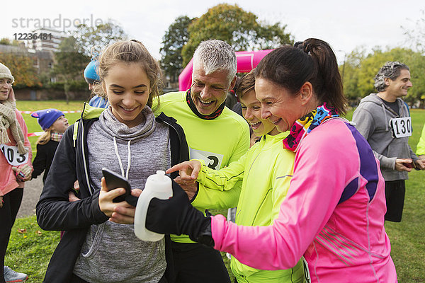 Familienläufer mit Smartphone beim Benefizlauf im Park