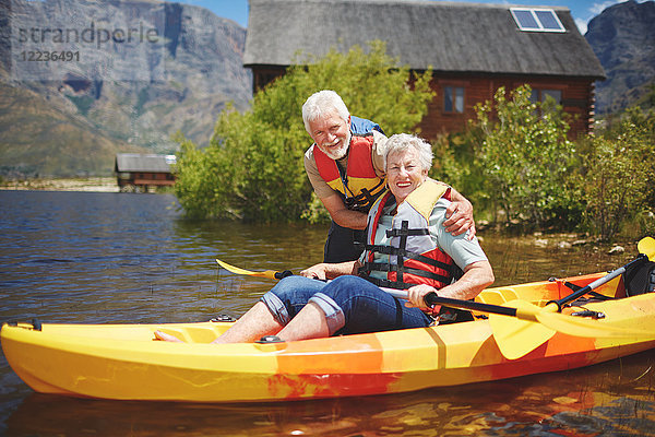 Portrait lächelndes aktives Seniorenpaar beim Kajakfahren auf dem sonnigen Sommersee