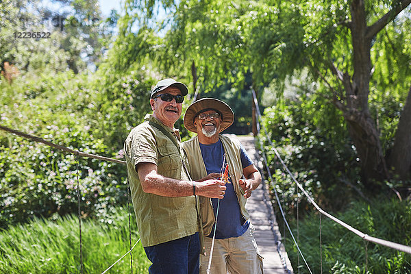 Portrait fröhlich aktive Senioren Freunde fischen auf sonniger Sommer-Fußgängerbrücke