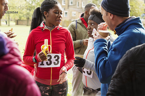 Läufer trinken Wasser und essen Banane beim Charity-Rennen im Park