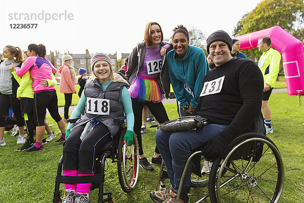 Portrait lächelnde Freunde im Rollstuhl beim Charity-Rennen im Park