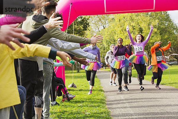 Enthusiastische Läuferinnen im Tutus beim Charity-Lauf im Park im Ziel
