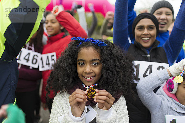 Portrait lächelnde Läuferin mit Medaille beim Benefizlauf im Park