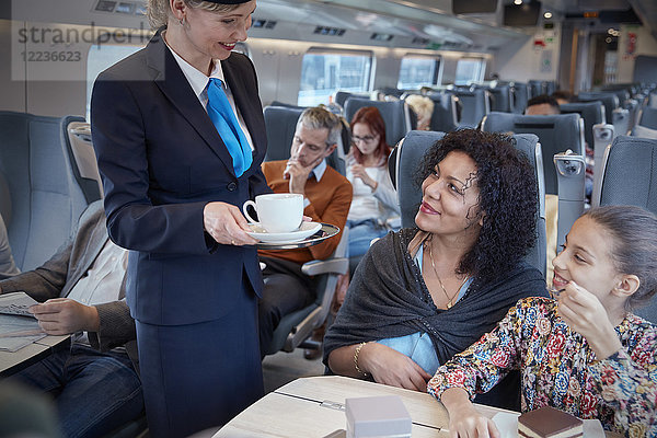 Begleiterin  die der Mutter mit der Tochter im Personenzug Kaffee serviert.