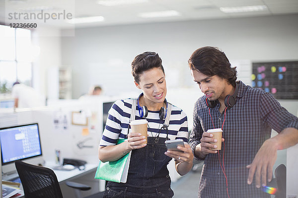 Kreative Geschäftsleute  die im Büro Kaffee trinken und ihr Smartphone benutzen