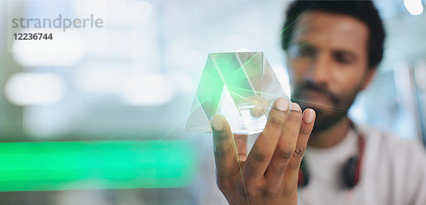Nahaufnahme eines innovativen männlichen Unternehmers  der den Prototyp eines Glasdreiecks untersucht