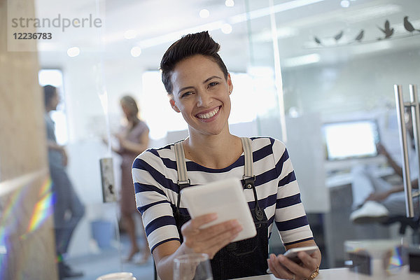 Porträt einer lächelnden  selbstbewussten  kreativen Geschäftsfrau  die ein digitales Tablet im Büro benutzt