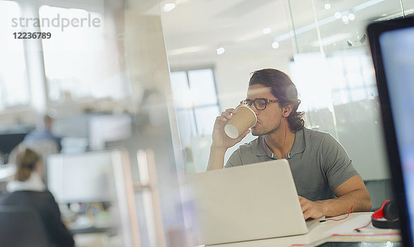 Kreativer Geschäftsmann trinkt Kaffee  arbeitet am Laptop im Büro