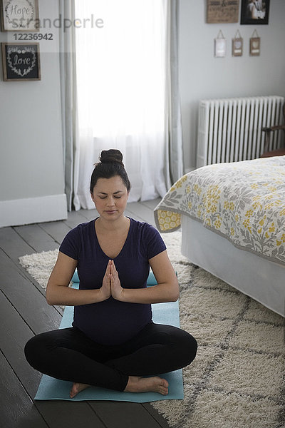 Schwangere Frau macht Yoga im Schlafzimmer