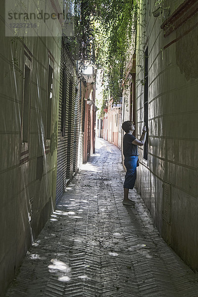 Spanien  Sevilla  Frau fotografiert mit Handy in den Gassen von Judeira