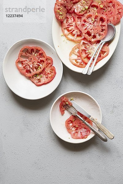 Rosa Tomatensalat mit gehackten Frühlingszwiebeln  Olivenöl  getrocknetem Oregano und Meersalzflocken
