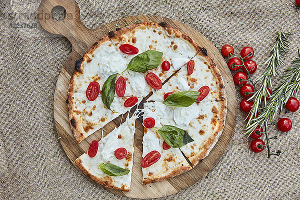 Eine Pizza mit Büffelmozzarella  Kirschtomaten und Basilikum