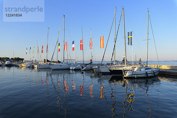 Eine Reihe von Booten und bunten Europaflaggen im Yachthafen am Gardasee (Lago di Garda) in Bardolino in Venetien  Italien