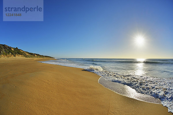 Die Brandung bricht an der Küste des Ninety Mile Beach am Paradise Beach  während die Sonne über dem Meer in Victoria  Australien  scheint.